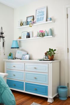 a white and blue dresser in a bedroom with pictures on the top shelf above it