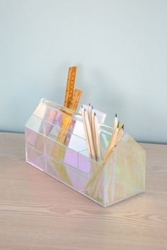 pencils and rulers in a clear container on a wooden table