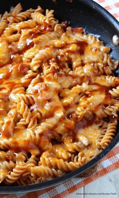 a skillet filled with macaroni and cheese on top of a checkered table cloth