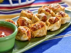 small appetizers on a green plate with dipping sauce in a bowl next to them