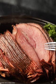 ham in a slow cooker with parsley on the side and a fork stuck into it