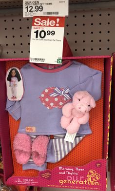 a pink teddy bear in a blue shirt and striped pants on display at a toy store