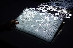 a person is holding an illuminated piece of paper in their hand and it looks like snowflakes