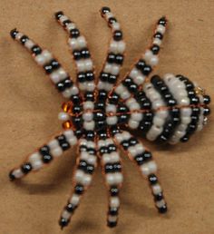 a beaded spider sitting on top of a piece of brown paper with black and white beads