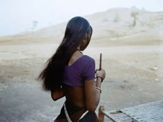 a woman with long hair is holding a cell phone in her hand and looking at the desert