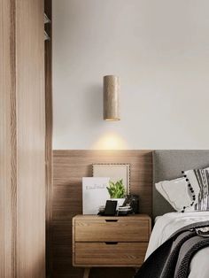 a bedroom with a bed, nightstand and lamp on the side table in front of it