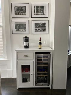 there is a wine cooler in the corner of this room with pictures on the wall