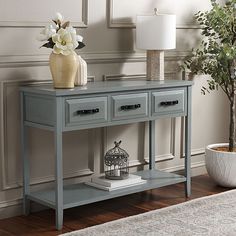 a grey console table with two drawers and a lamp