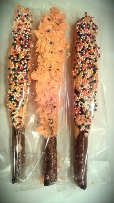 two corn on the cob sticks with sprinkles and other toppings