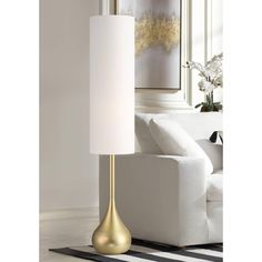 a gold lamp sitting on top of a table next to a white couch