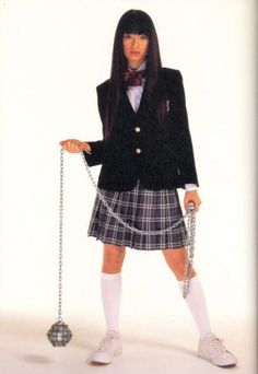 a woman in a school uniform holding a ball and chain