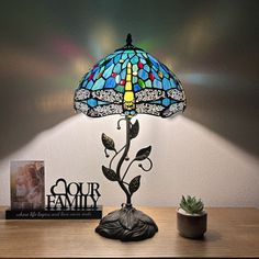 a lamp that is sitting on top of a table next to a book and potted plant