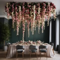 a dining room with flowers hanging from the ceiling and tables set up for an event