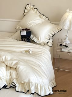 a bed with white sheets and pillows on top of it next to a night stand