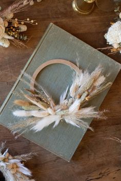 an old book with some feathers on top of it and flowers around the edges,