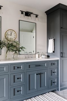 a bathroom with gray cabinets and two mirrors on the wall next to eachother