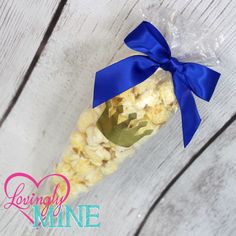 the popcorn is wrapped in plastic and tied with a blue ribbon on a white wooden background