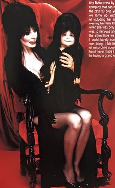 two women in black dresses sitting on a chair with their arms around each other's shoulders