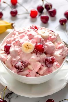 a white bowl filled with fruit and topped with banana slices, cherries and whipped cream