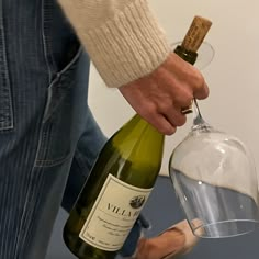 a person pouring wine into a glass with a corkscrew in it and a bottle on the table