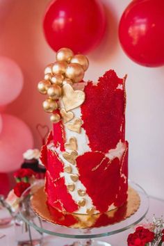 a red and white cake sitting on top of a table next to some pink balloons