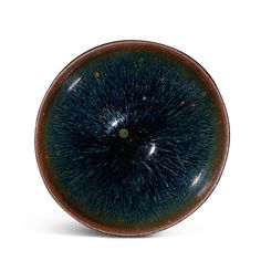 a brown and blue plate with black speckles in the center on a white background