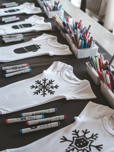 several t - shirts with snowflakes and crayons are lined up on a table