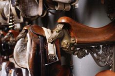 many different types of saddles hanging on the wall