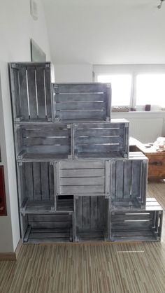 a stack of wooden crates sitting on top of a hard wood floor next to a window