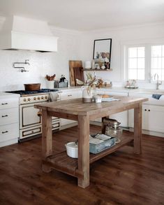 a wooden table sitting in the middle of a kitchen next to an oven and sink