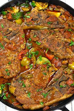 a pan filled with meat and vegetables on top of a wooden table next to a fork