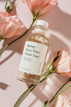 a bottle of facial toner next to pink flowers