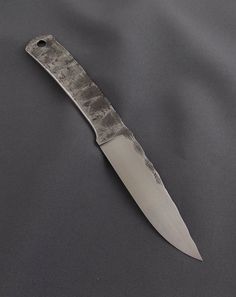 a knife is laying on top of a gray cloth with the blade still attached to it