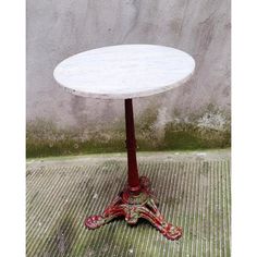 a white table sitting on top of a wooden floor next to a cement wall and green grass