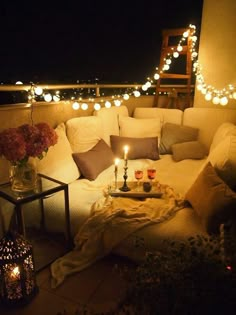 a couch sitting on top of a patio next to a table filled with flowers and candles