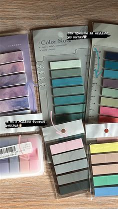 several different colors of sticky notes in a package on a wooden table with scissors and tape