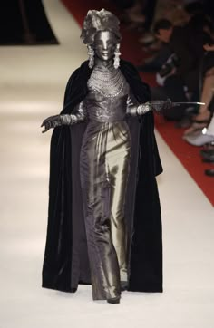 a woman is walking down the runway in a costume