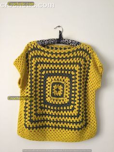 a yellow and black crocheted shirt hanging on a wall