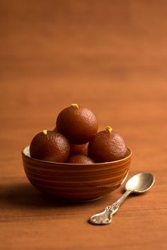 a bowl filled with fruit sitting on top of a wooden table next to a spoon