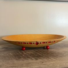 a wooden bowl sitting on top of a table next to a white wall and red legs