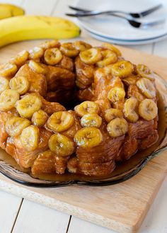 a banana bundt cake sitting on top of a wooden cutting board next to bananas