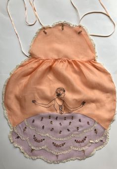 Soft lavender and peach organdy together in this vintage apron make a pretty cover. The Southern Belle's lavender skirt is the skirt of the vintage apron. Embroidery of the figure and flowers, and lace in layers and all around the vintage full apron add to the its charm. Ribbon ties hold the vintage apron on at the neck and waist. The vintage belle apron is 33 inches long and 15 inches at the waist. Belle Apron, Cottagecore Apron, Apron Embroidery, Lavender And Peach, Lavender Skirt, Full Apron, Vintage Apron, Southern Lady, Southern Ladies