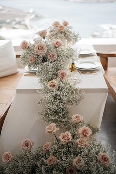 the table is set with pink roses and baby's breath