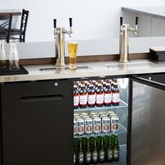 a refrigerator filled with lots of drinks next to a table full of bottles and glasses