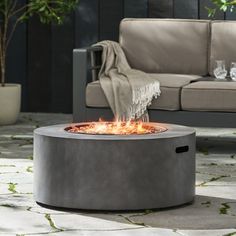 a fire pit sitting on top of a stone floor next to a couch and table