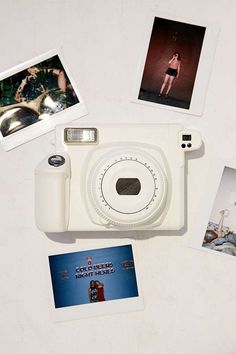 a white camera sitting on top of a table next to polaroid pictures and photos