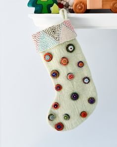 a christmas stocking hanging from a shelf with buttons on it and a toy train in the background