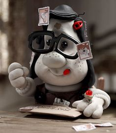 a stuffed animal with glasses on top of a wooden table next to papers and pens