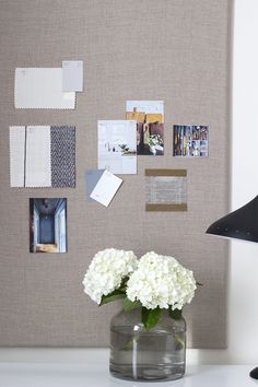 a vase filled with white flowers sitting on top of a table next to a wall