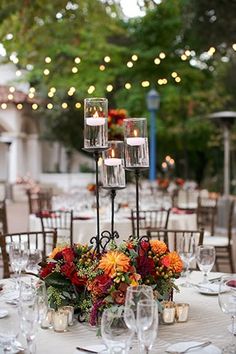 the centerpieces on this table are filled with flowers and candles for an elegant touch